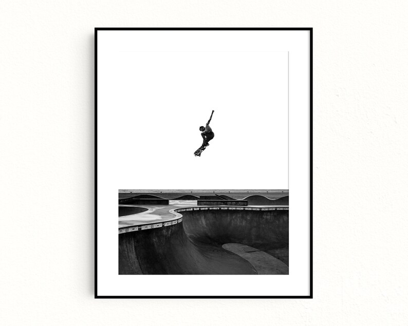 Peut inclure: Tirage encadr&eacute; en noir et blanc d'un skateur en plein saut au-dessus d'un skatepark. La silhouette du skateur se d&eacute;tache sur un ciel blanc, avec les courbes en b&eacute;ton du parc en contrebas. Une &oelig;uvre d'art contemporaine.