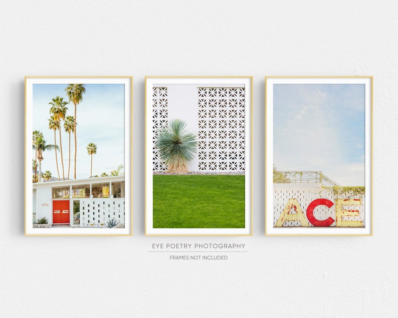 May include: Three framed prints of mid-century modern architecture in Palm Springs, California. The first print shows a white house with a red door and palm trees. The second print shows a white wall with a geometric pattern and a yucca plant. The third print shows a vintage sign that reads "ACE" in red and yellow letters.