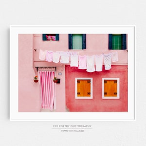 Peut inclure: Un b&acirc;timent rose avec des bordures et des fen&ecirc;tres blanches. Des v&ecirc;tements sont suspendus &agrave; une ligne &agrave; l'ext&eacute;rieur du b&acirc;timent. Les v&ecirc;tements sont blancs et roses. Il y a des fleurs dans des pots sur le b&acirc;timent.