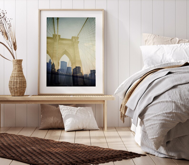 Puede incluir: Una fotograf&iacute;a enmarcada del puente de Brooklyn en la ciudad de Nueva York. La imagen es una fotograf&iacute;a de estilo vintage con un tono sepia descolorido. El puente est&aacute; enfocado, mientras que el horizonte de la ciudad en el fondo est&aacute; desenfocado.