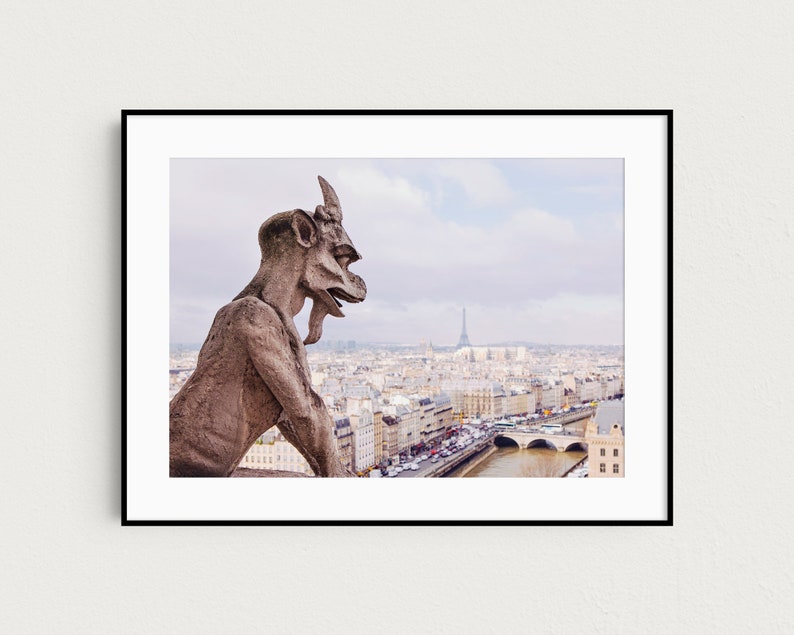 May include: A stone gargoyle sits atop a building overlooking the city of Paris, France. The Eiffel Tower is visible in the distance.