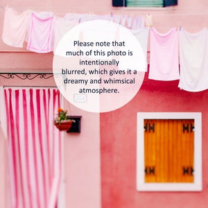 Peut inclure: Un b&acirc;timent rose avec une fen&ecirc;tre blanche et une porte blanche. Il y a des rideaux ray&eacute;s rose et blanc dans l'entr&eacute;e. Des v&ecirc;tements sont suspendus &agrave; une corde &agrave; linge &agrave; l'ext&eacute;rieur du b&acirc;timent. Le texte "Veuillez noter qu'une grande partie de cette photo est intentionnellement floue, ce qui lui donne une ambiance r&ecirc;veuse et fantaisiste." est &eacute;crit dans un cercle blanc sur le b&acirc;timent.