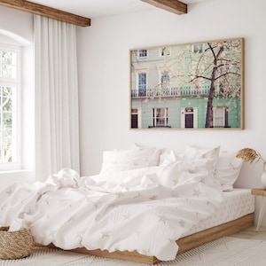 May include: A white bed with a white duvet cover and white pillowcases. The duvet cover has a subtle star pattern. The bed is in a bedroom with a window and a framed print of a building with a tree in front of it.