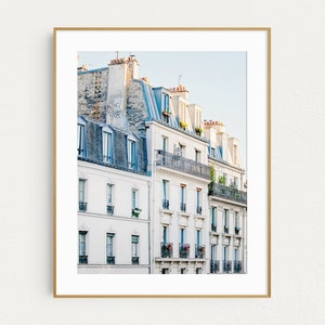 Puede incluir: Una fotograf&iacute;a de un edificio blanco con m&uacute;ltiples ventanas y balcones en Par&iacute;s, Francia. El edificio tiene un techo azul y est&aacute; rodeado de otros edificios.