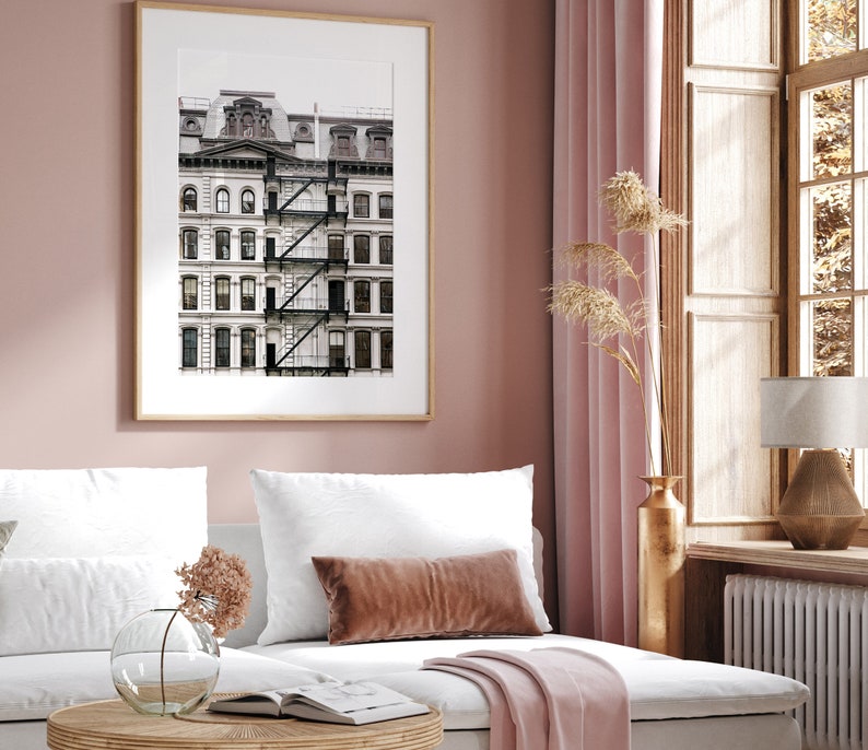 Puede incluir: Una fotograf&iacute;a en blanco y negro enmarcada de un edificio blanco con una escalera de incendios. El edificio tiene varias ventanas y est&aacute; sobre un fondo gris claro. La foto est&aacute; colgada en una pared rosa claro.