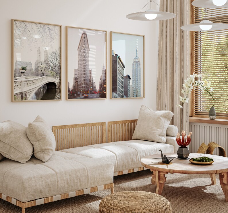 K&ouml;nnte beinhalten: Ein hellbeiges Ecksofa mit drei Kissen, einem Holzrahmen und einer gewebten Textur. Das Sofa steht in einem Wohnzimmer mit drei gerahmten Schwarzwei&szlig;-Stadtansichten, einem Holz-Couchtisch und einem geflochtenen Hocker.