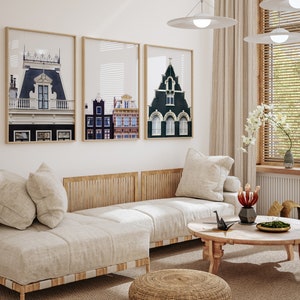 May include: A living room with a white couch, a coffee table, and three framed prints of buildings. The prints are black and white and feature different architectural styles. The couch is white and has a wooden frame. The coffee table is round and has a wooden top. The room is decorated with plants and other decorative items.