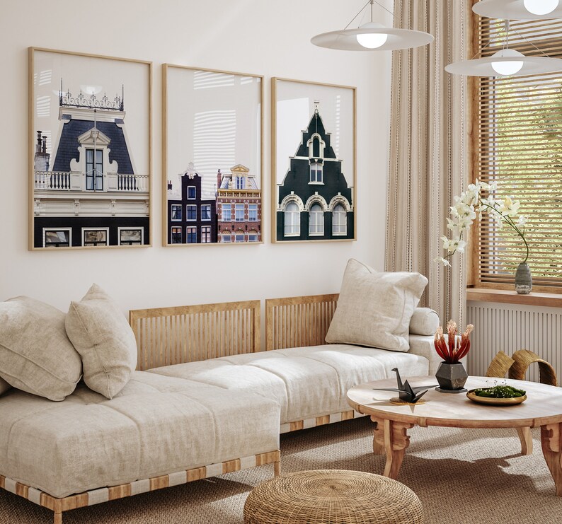 May include: A living room with a white couch, a coffee table, and three framed prints of buildings. The prints are black and white and feature different architectural styles. The couch is white and has a wooden frame. The coffee table is round and has a wooden top. The room is decorated with plants and other decorative items.