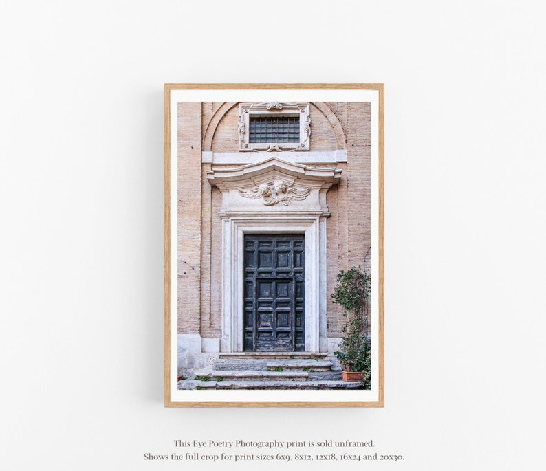 May include: A photograph of a weathered, pale pink building with a dark blue wooden door. The door is framed by a white stone archway with a small window above it. The building is in a slightly faded, vintage style.