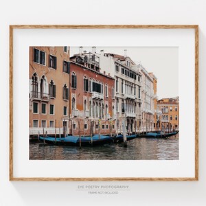 May include: A photograph of a canal in Venice, Italy. The canal is lined with colorful buildings, and there are several gondolas docked along the edge of the water.