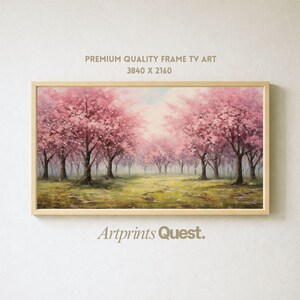 Op de afbeelding: Een ingelijst landschapsschilderij van een pad door een bosje kersenbloesem bomen met roze bloemen. Het kunstwerk zit in een licht houten lijst. De tekst "PREMIUM QUALITY FRAME TV ART 3840 X 2160" staat bovenaan en "Artprints Quest" onderaan.