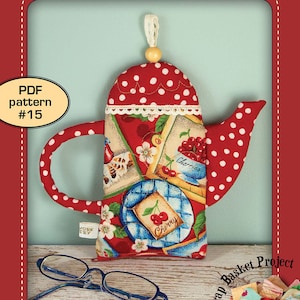 Puede incluir: Una bolsa con forma de tetera roja y blanca con estampado de cerezas. La bolsa está hecha de tela y tiene un ribete de encaje blanco. La bolsa está sobre una superficie de madera con unas gafas y una cesta de recortes de tela. El texto "PATCHWORK*POTTERY" está en la parte superior de la imagen. El texto "PDF pattern #15" está en un círculo en la parte superior izquierda de la imagen. El texto "TEAPOT POUCH" está en la parte inferior de la imagen. El texto "a Scrap Basket Project" está en un círculo en la parte inferior derecha de la imagen.