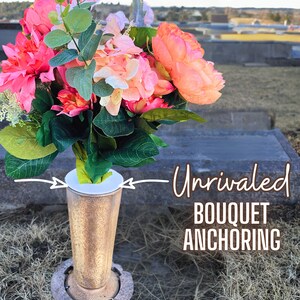 Puede incluir: Un ramo de flores rosas y blancas en un jarrón dorado con base blanca. El jarrón está sobre una superficie marrón con hierba seca. El texto "Unrivaled Bouquet Anchoring" está escrito en blanco sobre fondo negro.