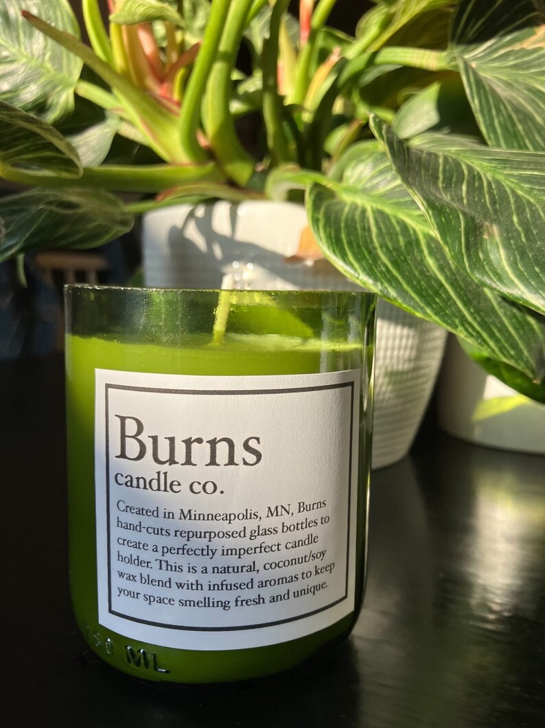 Pu&ograve; includere: Un barattolo di vetro verde per candele con un'etichetta bianca su cui &egrave; scritto "Burns candle co.". L'etichetta include anche il testo "Creato a Minneapolis, MN, Burns taglia a mano bottiglie di vetro riutilizzate per creare un portacandele imperfetto. Questa &egrave; una miscela di cera naturale, cocco e soia, con aromi infusi per mantenere il tuo spazio profumato di fresco e unico."