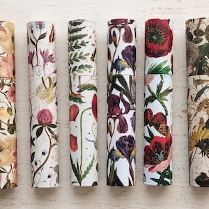 May include: Six cylindrical cardboard tubes arranged vertically, each featuring distinct botanical illustrations. The designs include various floral patterns such as yellow flowers, pink clover, red poppies, purple irises, and green foliage.