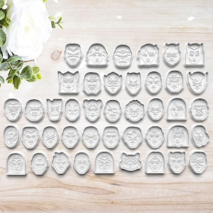 May include: A set of 36 white plastic cookie cutters featuring various superhero character faces.