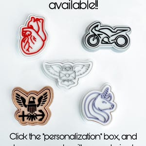May include: Five different cookie cutters, each with a two-tone design. The cutters are shaped like a heart, a motorcycle, an owl, an eagle, and a unicorn. The text "Two-tone options available!!" is at the top of the image. The text "Click the "personalization" box, and leave us a note with your desired "background" and "design" colors!" is at the bottom of the image.