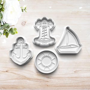 May include: Set of four white plastic cookie cutters shaped like a lighthouse, sailboat, anchor, and life preserver.