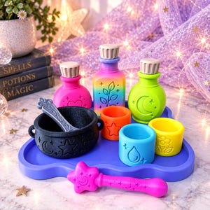 May include: A set of colorful plastic potion-making toys including a black cauldron with a silver spoon, three small cups in orange, blue, and yellow, three bottles with stoppers, and a pink star-topped wand, all arranged on a blue tray.