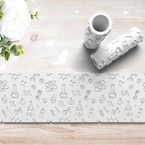 May include: Two white cylindrical rollers with a science-themed design, featuring beakers, atoms, and molecular structures. The rollers are on a white surface with a matching patterned border. A bouquet of white flowers is in the background.