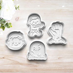 May include: Four white plastic cookie cutters in a Halloween theme. The shapes include a zombie, a zombie hand rising from the ground, a tombstone with "RIP" engraved, and a cartoon face.