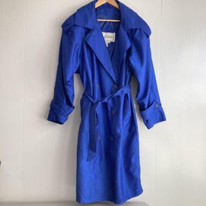 May include: A royal blue double-breasted trench coat with a belt and a label that reads "La Vogue".