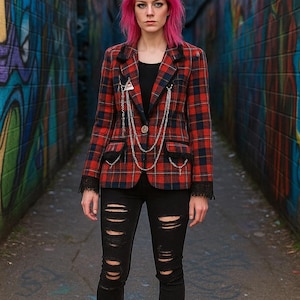 May include: A red and black plaid blazer with silver chain detailing, paired with black ripped jeans and red boots. The outfit is worn with a black top and set against a graffiti-covered alleyway.