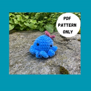 Könnte beinhalten: Ein blauer gehäkelter Oktopus mit schwarzen Augen und einer rosa Blume oben drauf. Der Oktopus sitzt auf einem grauen Stein mit grünen Pflanzen im Hintergrund. Der Text "PDF PATTERN ONLY" ist in einem weißen Kreis auf dem Bild geschrieben.