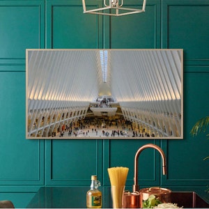 May include: A framed photograph of a large, modern building with a white interior and a high ceiling. The building is filled with people and has a geometric design.