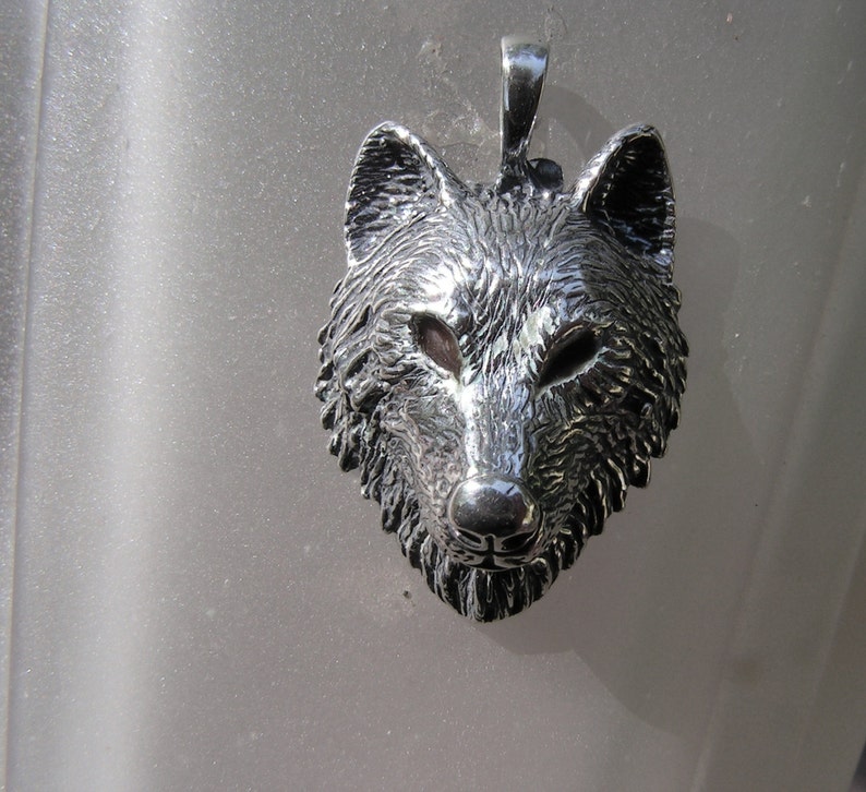 K&ouml;nnte beinhalten: Ein silberner Wolfskopf-Anh&auml;nger mit einem detaillierten, strukturierten Design. Der Anh&auml;nger ist eine realistische Darstellung eines Wolfskopfes mit einer spitzen Nase, spitzen Ohren und einem wilden Ausdruck.