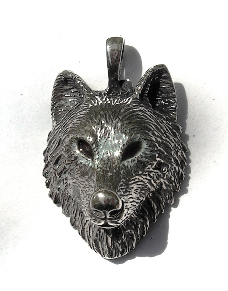 K&ouml;nnte beinhalten: Ein silberner Wolfskopf-Anh&auml;nger mit detailliertem Design. Der Anh&auml;nger ist eine realistische Darstellung eines Wolfskopfes mit Fell und Gesichtsz&uuml;gen.