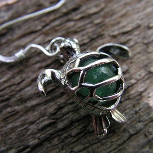 Pu&ograve; includere: Orecchino a forma di tartaruga in argento con un cabochon di vetro verde all'interno. La tartaruga &egrave; dettagliata con un design a guscio e un anello di sospensione.
