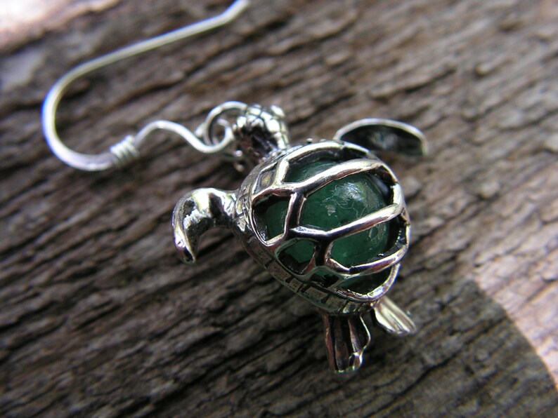 Pu&ograve; includere: Orecchino a forma di tartaruga in argento con un cabochon di vetro verde all'interno. La tartaruga &egrave; dettagliata con un design a guscio e un anello di sospensione.