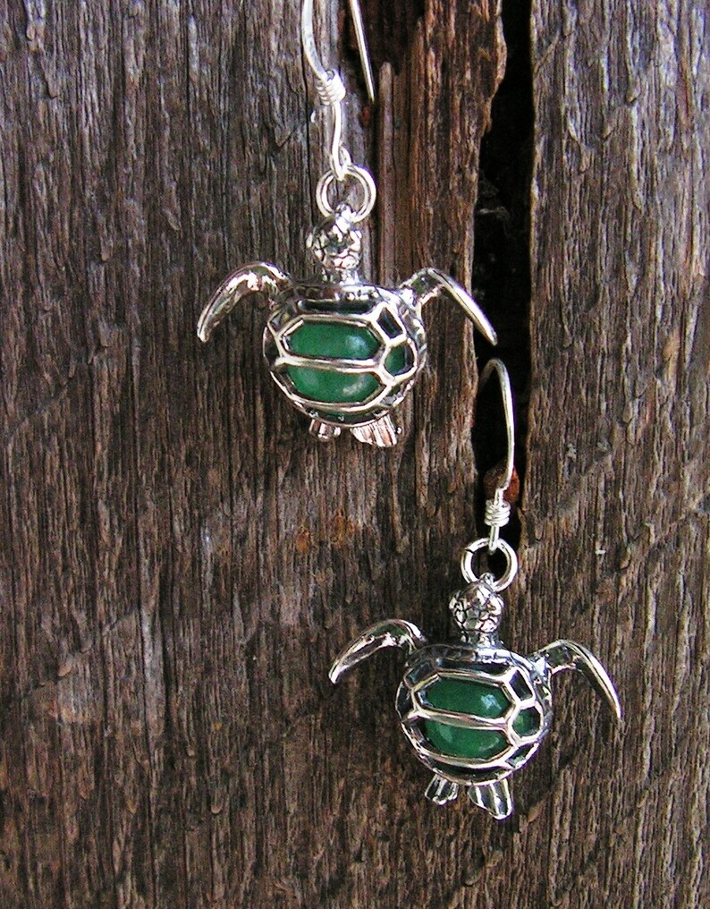 Pu&ograve; includere: Un paio di orecchini d'argento con un design a tartaruga in pietra preziosa verde.