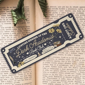 Könnte beinhalten: Ein blaues und goldenes Lesezeichen mit dem Text "Lifetime Member of the Dark Academia Book Club" und einer Schwarzweißillustration eines Buches, einer Brille und einer Katze. Das Lesezeichen enthält auch den Text "Dress Code: Literary Chic" und "Time: Midnight".