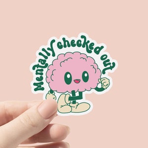 以下が含まれることがあります： 緑色の輪郭と「Mentally checked out」という緑色の筆記体で書かれたテキストを持つ、ピンク色の脳の漫画キャラクターです。