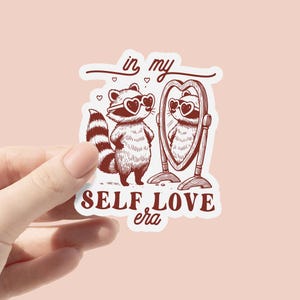 Autocollant en vinyle de l'ère de l'amour de moi | Stickers motivants | Autocollants d'affirmation | Raton laveur drôle | Stickers pour ordinateur portable | Décalcomanies imperméables