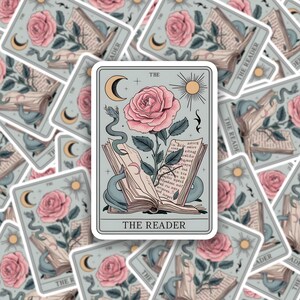 May include: A tarot card illustration featuring a rose with a snake wrapped around an open book. The card is titled "The Reader" and has a crescent moon, sun, and text in the background.