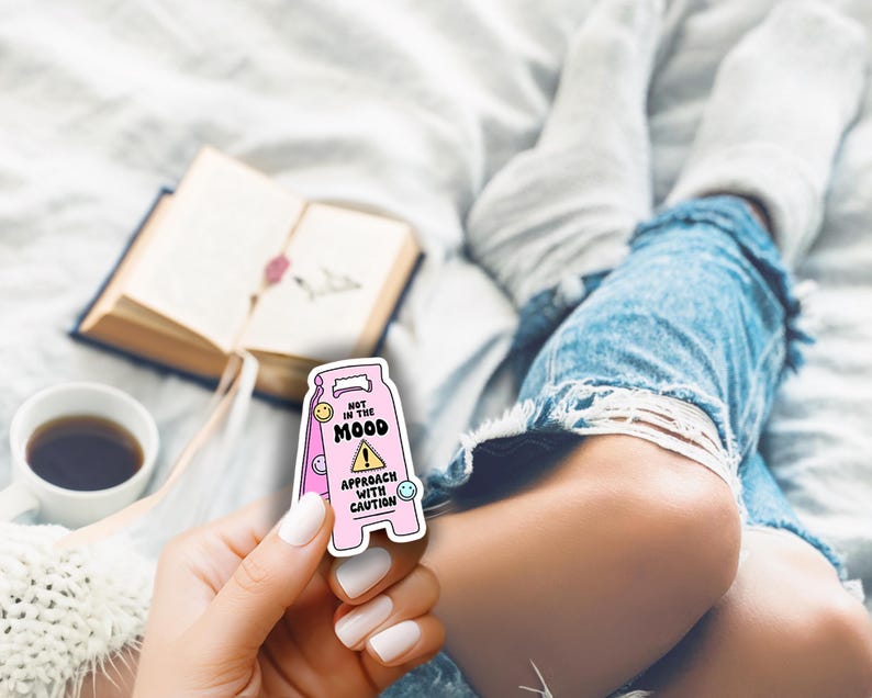 Op de afbeelding: Roze en witte waarschuwingsteken sticker met de tekst "Niet in de stemming! Benader met voorzichtigheid." en een geel uitroepteken. De sticker heeft een cartoon smiley op elke hoek.