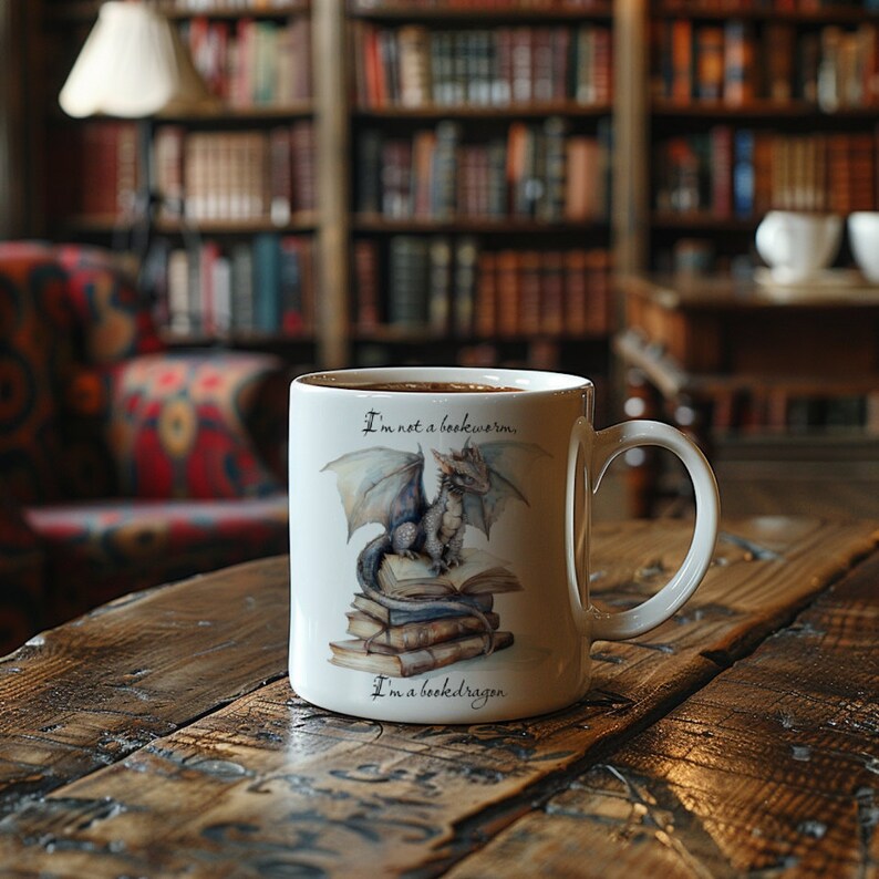 May include: A white ceramic mug with a gray dragon sitting on a stack of books. The mug has the text "I'm not a bookworm, I'm a book dragon."