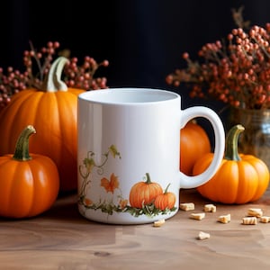 May include: White ceramic mug with a pumpkin design, featuring orange pumpkins and green vines. The mug is surrounded by several orange pumpkins and fall foliage, set on a wooden surface.