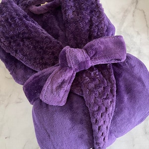 May include: A purple plush robe with a shawl collar and a tie belt.