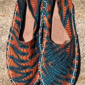 May include: A pair of orange and teal espadrilles with a white stitching detail. The shoes have a geometric pattern.