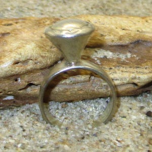 May include: A silver ring with a rounded, dome-shaped top. The ring is simple and minimalist in design.