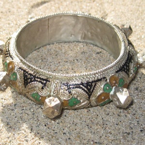 Peut inclure: Un bracelet en argent avec des détails en émail vert, noir et or. Le bracelet a six pointes décoratives autour de la circonférence.