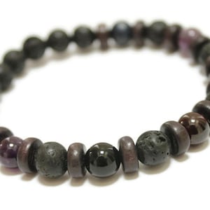 May include: A black lava rock and gemstone bracelet with dark purple, black, and blue beads.