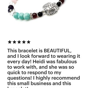 May include: A beaded bracelet featuring a silver turtle charm and a variety of colorful beads, including turquoise, pink, purple, and clear beads. The bracelet has a silver clasp. The text on the image says: "This bracelet is BEAUTIFUL..."