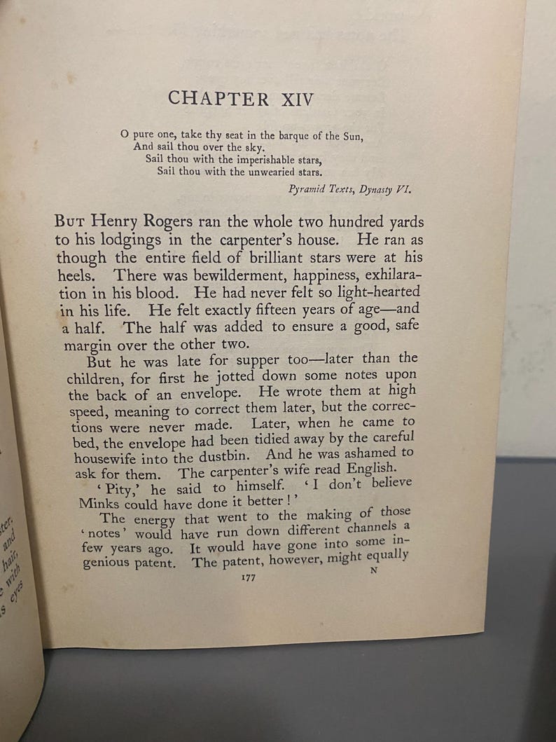 May include: Open book with text from "Chapter XIV" of a book. The text is in black font on aged, off-white paper. The text includes poetry and prose. The page number "177" is visible at the bottom of the page.