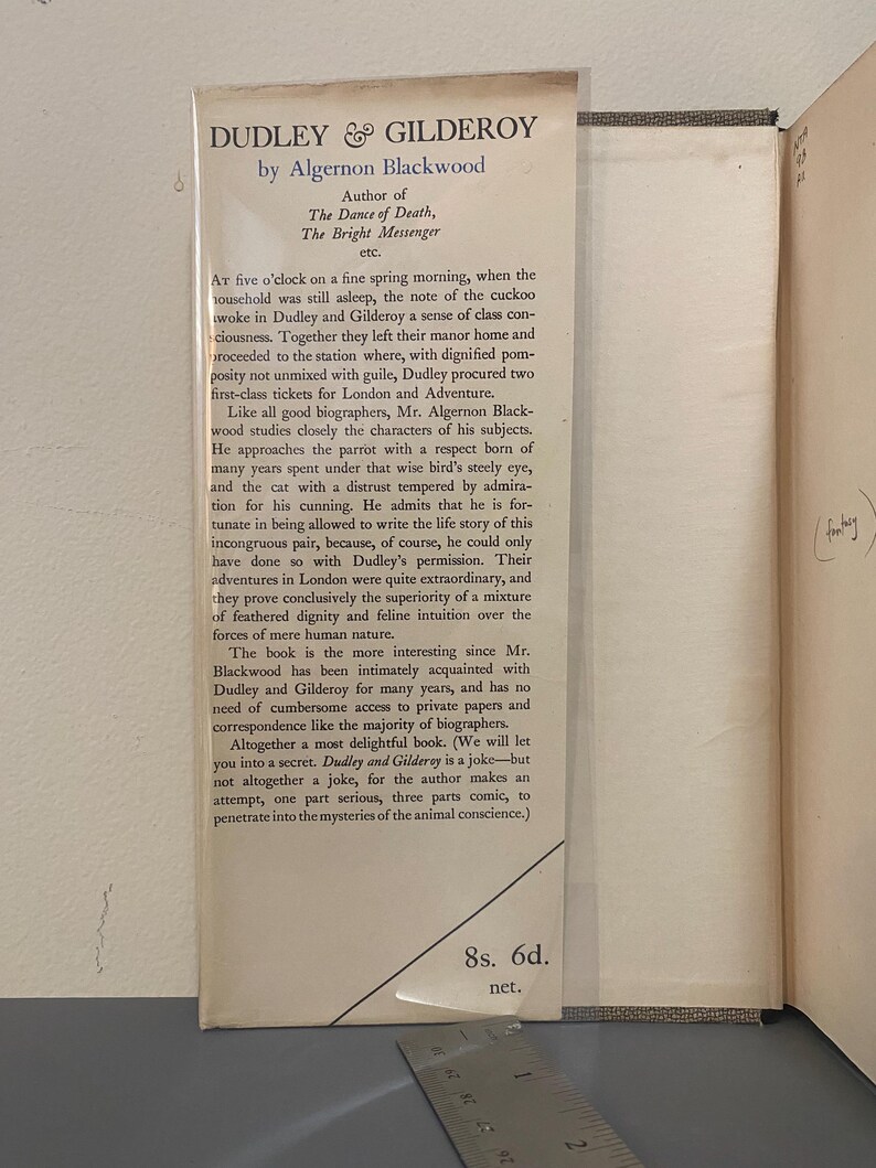 May include: A vintage book page with the title "Dudley & Gilderoy" by Algernon Blackwood. The text describes the book's characters and themes, with a price of 8s. 6d. visible. The page is aged with a slight yellowing.