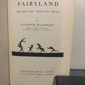 May include: A vintage book titled "A Prisoner in Fairyland" by Algernon Blackwood. The cover features a silhouette of figures in motion. Published in 1913 by Macmillan and Co., Limited, St. Martin's Street, London.